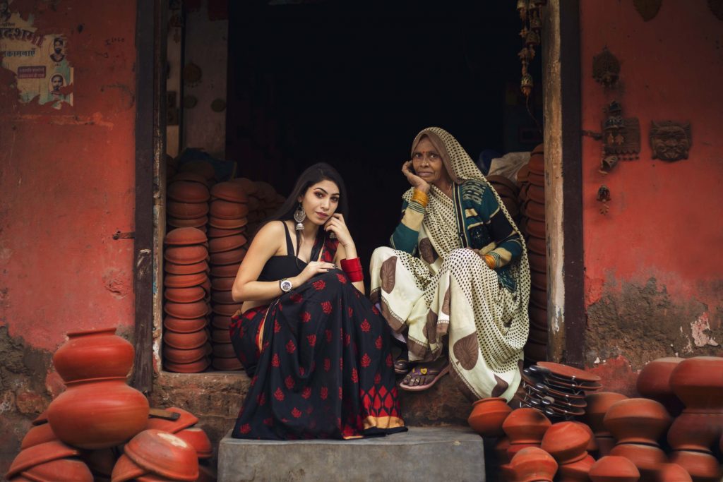 Deux femmes en vêtements traditionnels parmi des pots en terre cuite, montrant la culture indienne.