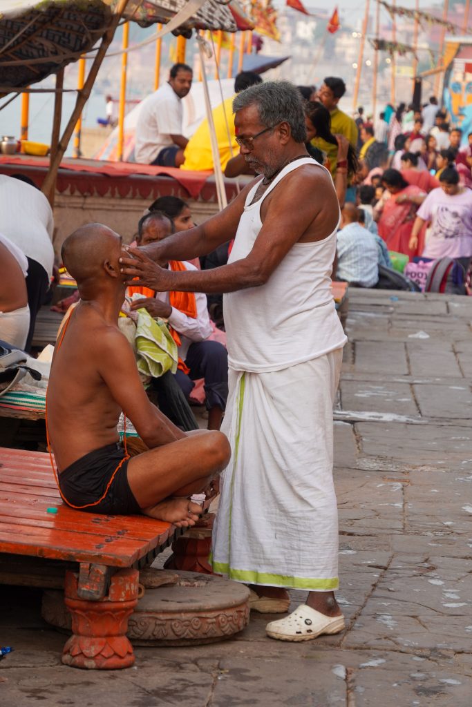 Coiffeur de rue coupant les cheveux d’un client sur les ghats de Varanasi