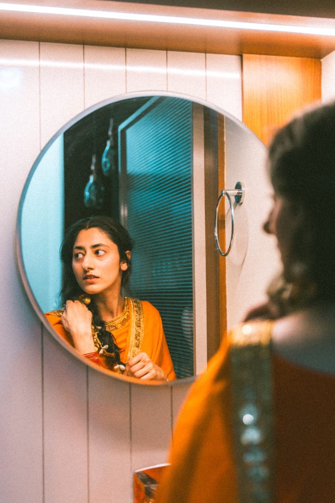 Femme indienne en robe traditionnelle orange se regardant dans un miroir