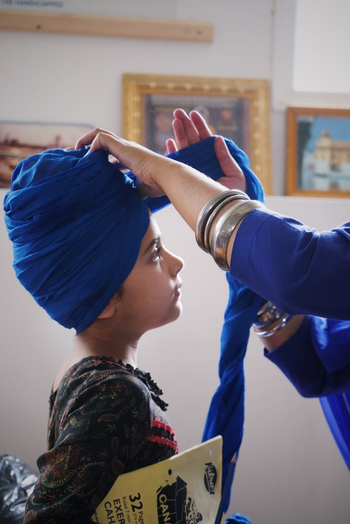 Un homme aide un enfant à porter un turban bleu traditionnel